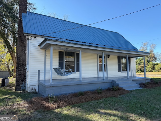 view of front of property with a front yard, a porch, and cooling unit