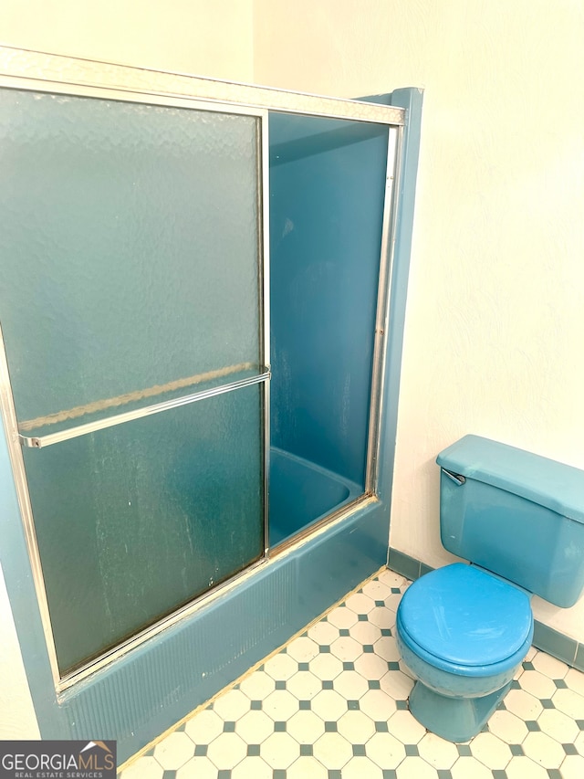 bathroom featuring bath / shower combo with glass door and toilet