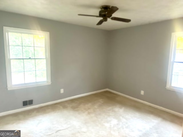 unfurnished room with ceiling fan, carpet floors, and plenty of natural light