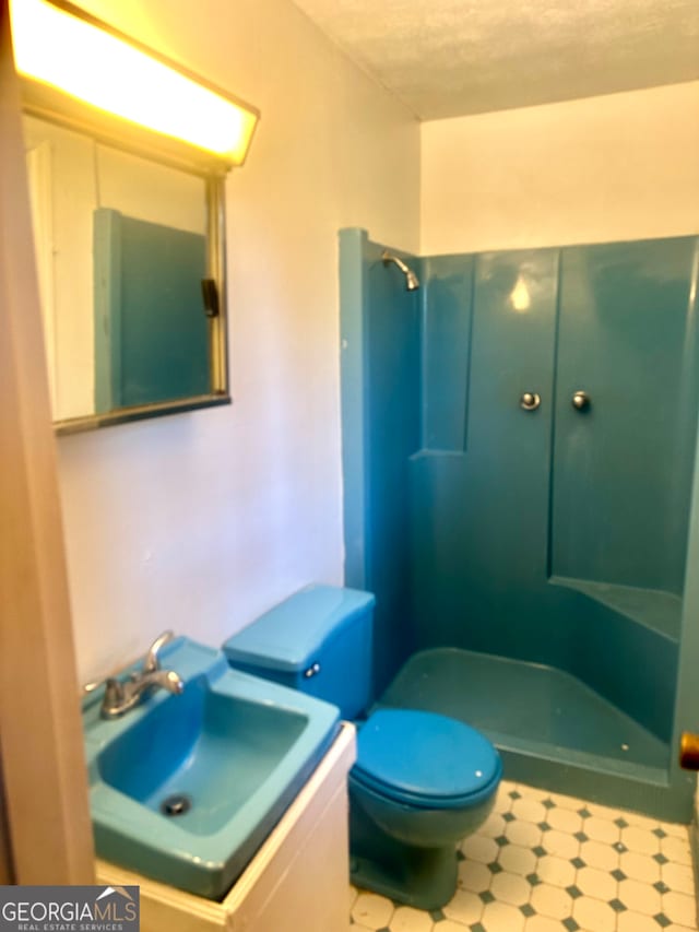 bathroom with walk in shower, vanity, a textured ceiling, and toilet