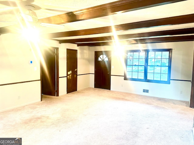 carpeted spare room with beamed ceiling