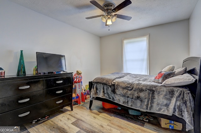 bedroom with light hardwood / wood-style floors, a textured ceiling, and ceiling fan