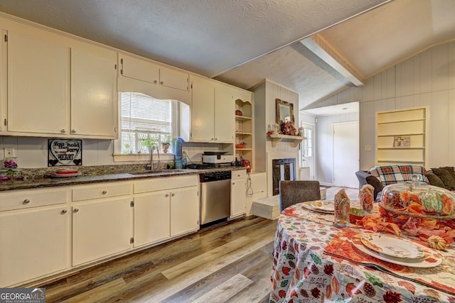 kitchen featuring stainless steel dishwasher, wooden walls, lofted ceiling, and light hardwood / wood-style floors