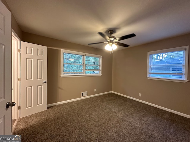 unfurnished bedroom featuring ceiling fan and dark carpet