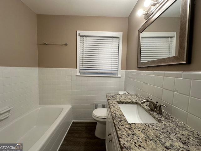 bathroom featuring tile walls, wood-type flooring, vanity, toilet, and a washtub