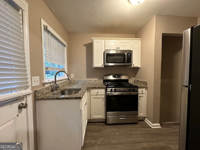 kitchen featuring stainless steel appliances, dark stone counters, sink, dark hardwood / wood-style floors, and white cabinetry