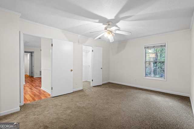 unfurnished bedroom featuring carpet, a textured ceiling, ceiling fan, and crown molding