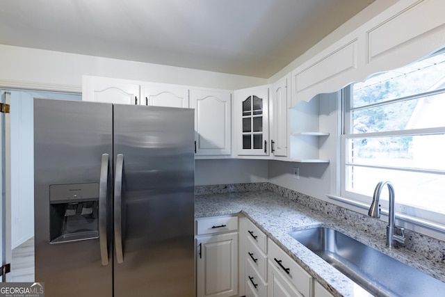 kitchen featuring white cabinets, stainless steel fridge with ice dispenser, light stone countertops, and sink