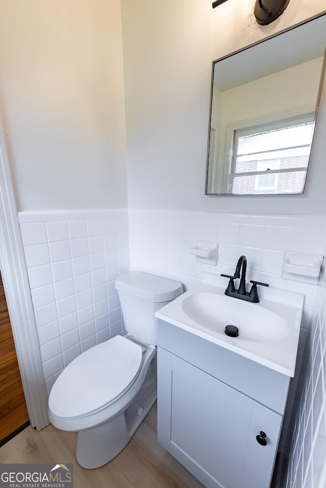 bathroom with hardwood / wood-style flooring, vanity, toilet, and tile walls