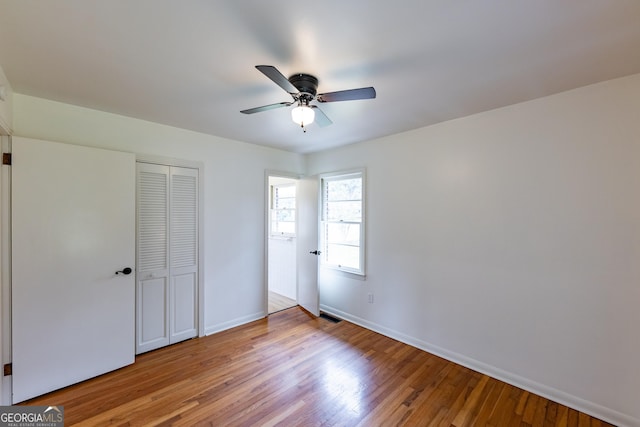 unfurnished bedroom with ceiling fan, a closet, and light wood-type flooring