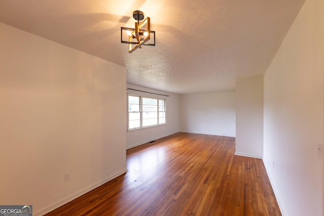 unfurnished room with dark hardwood / wood-style flooring and a notable chandelier