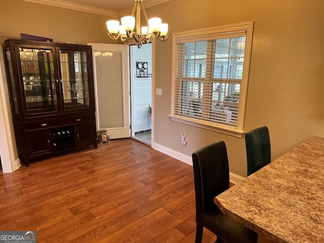 dining area with ornamental molding, wood-type flooring, and an inviting chandelier