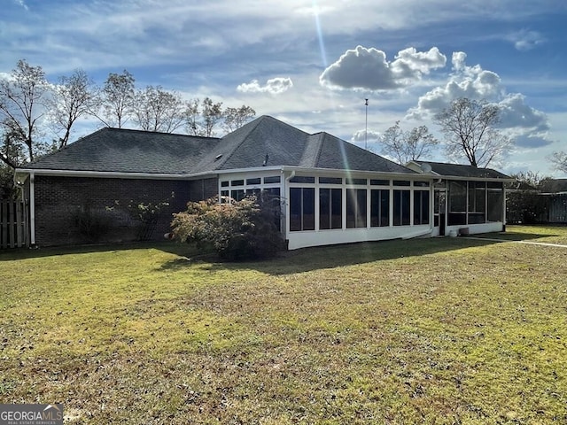 rear view of property featuring a sunroom and a yard