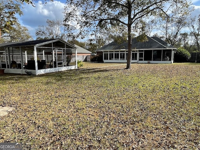 rear view of property featuring a lawn and a sunroom