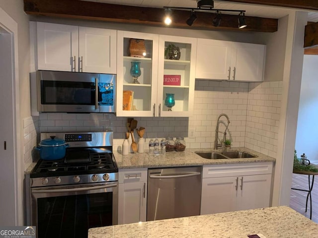 kitchen featuring stainless steel appliances, white cabinetry, sink, and light stone counters