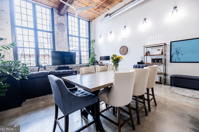 dining space with a high ceiling, a wealth of natural light, concrete floors, and wooden ceiling