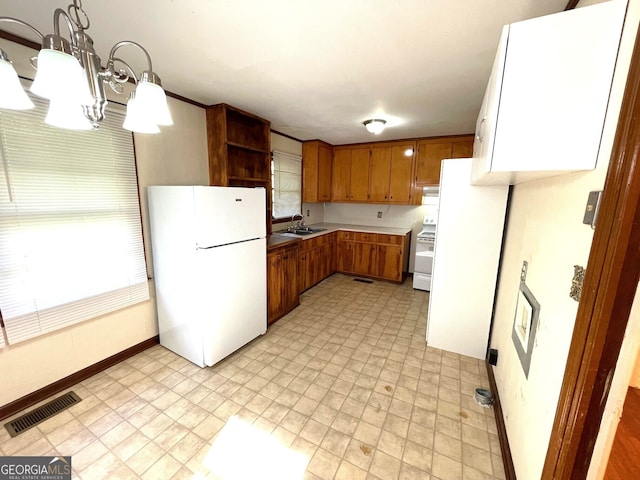 kitchen featuring pendant lighting, white appliances, and sink