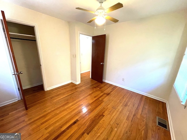 unfurnished bedroom featuring hardwood / wood-style flooring, ceiling fan, and a closet