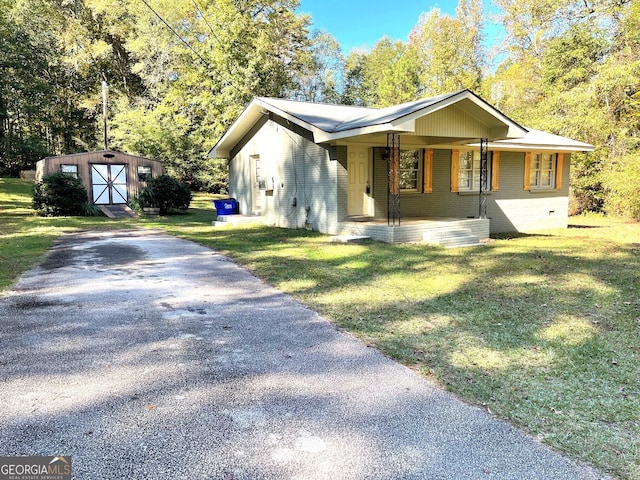 single story home with a porch, a front yard, and a storage unit