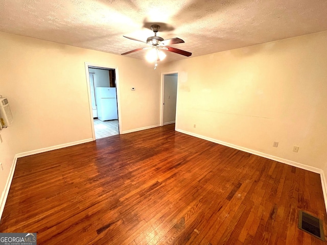 empty room with ceiling fan, wood-type flooring, and a textured ceiling