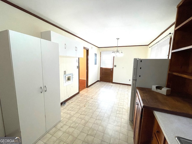 kitchen featuring ornamental molding, white cabinetry, white refrigerator, pendant lighting, and a chandelier