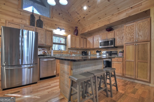 kitchen with plenty of natural light, high vaulted ceiling, a kitchen breakfast bar, and stainless steel appliances