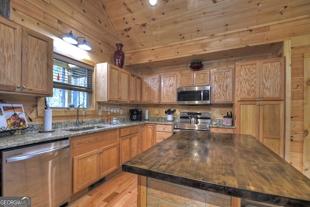 kitchen with lofted ceiling, sink, wood counters, light wood-type flooring, and appliances with stainless steel finishes