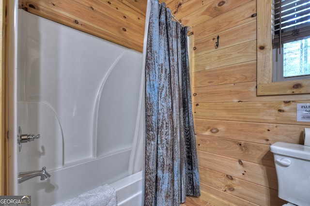 bathroom featuring wood walls, toilet, and shower / tub combo with curtain