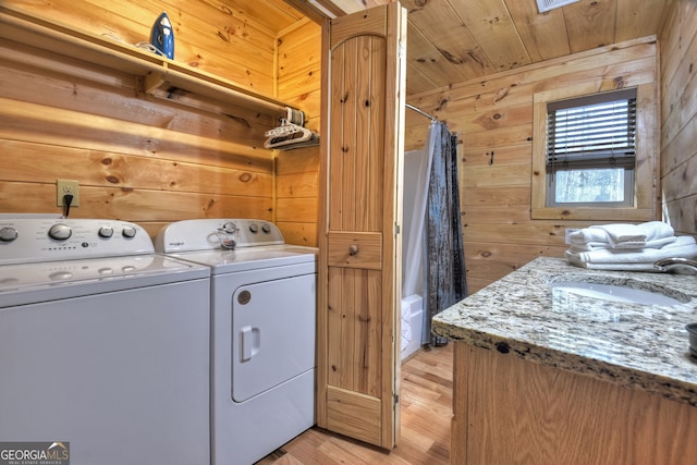 washroom with light wood-type flooring, wooden walls, sink, and wooden ceiling