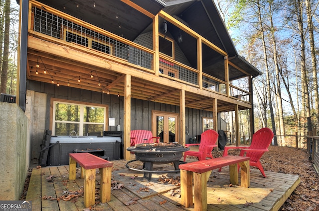 wooden deck with a hot tub, french doors, and a fire pit