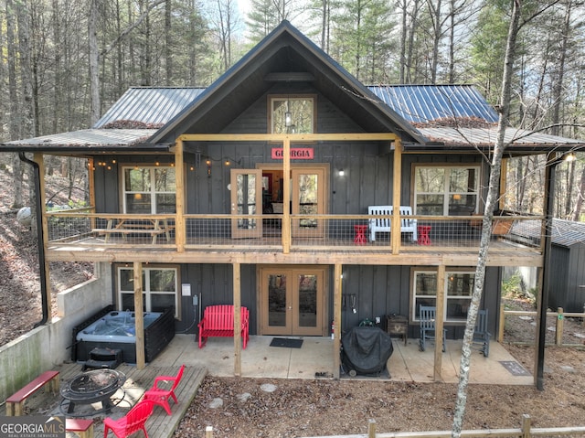 rear view of house featuring an outdoor fire pit, a hot tub, french doors, and a patio area