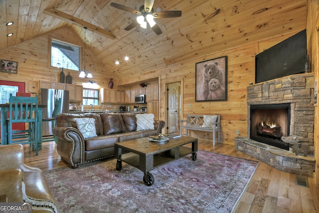 living room featuring wooden ceiling, ceiling fan, high vaulted ceiling, a fireplace, and wood-type flooring