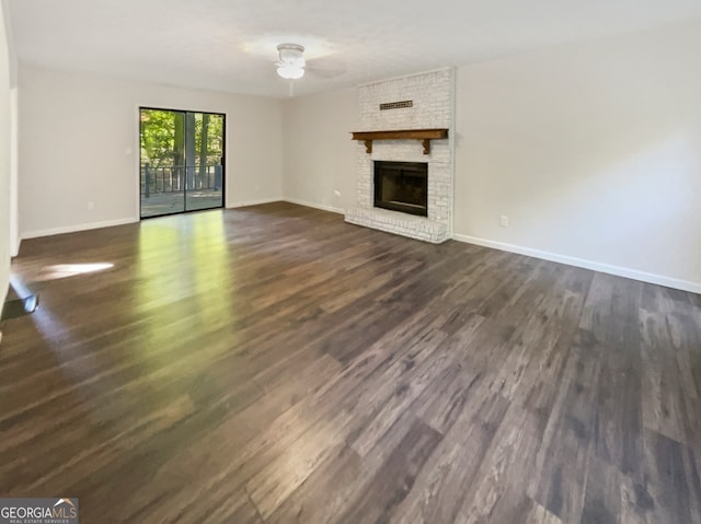 unfurnished living room with dark hardwood / wood-style flooring and a brick fireplace