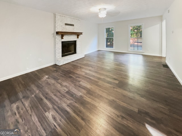 unfurnished living room featuring ceiling fan, a textured ceiling, dark hardwood / wood-style floors, and a fireplace