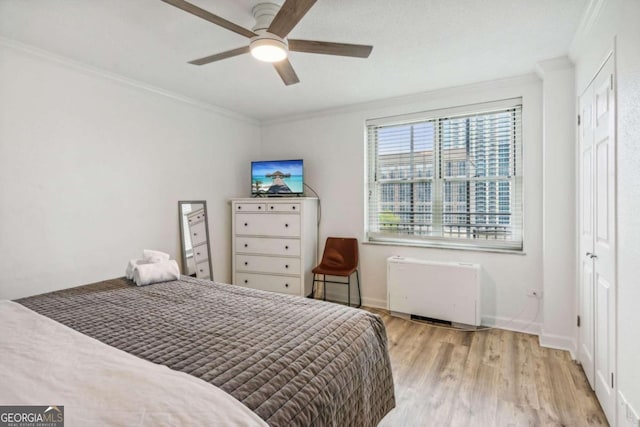 bedroom with radiator, a closet, ornamental molding, light wood-type flooring, and ceiling fan