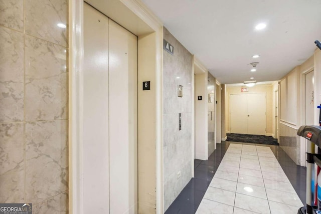 corridor featuring tile walls, tile patterned flooring, and elevator