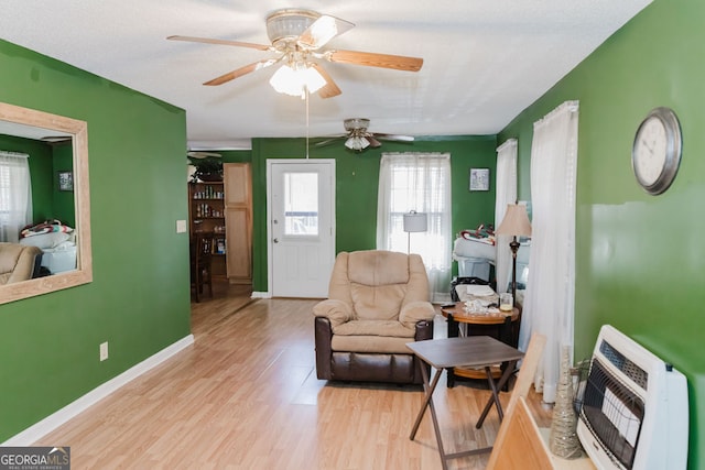 sitting room with ceiling fan, light wood-type flooring, and heating unit