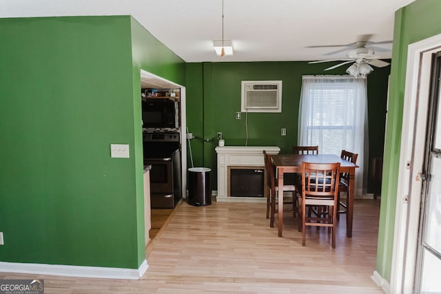 dining area featuring ceiling fan, light hardwood / wood-style floors, and a wall mounted air conditioner