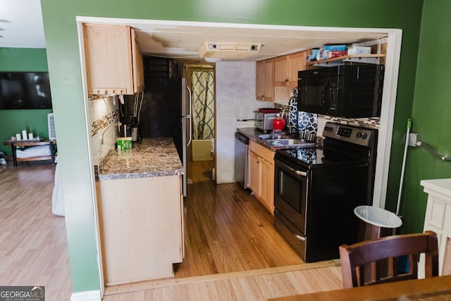 kitchen featuring decorative backsplash, light brown cabinetry, light hardwood / wood-style floors, and black appliances