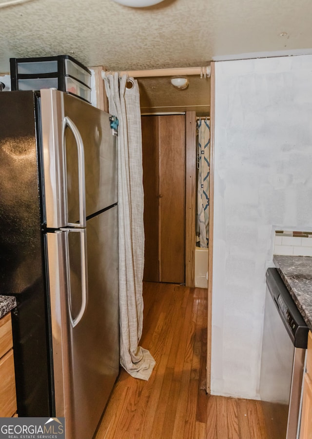 kitchen featuring a textured ceiling, light wood-type flooring, stainless steel appliances, and light brown cabinetry