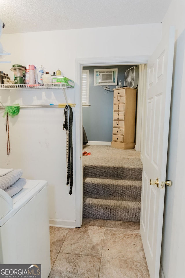 laundry area featuring a textured ceiling, tile patterned flooring, and a wall mounted air conditioner