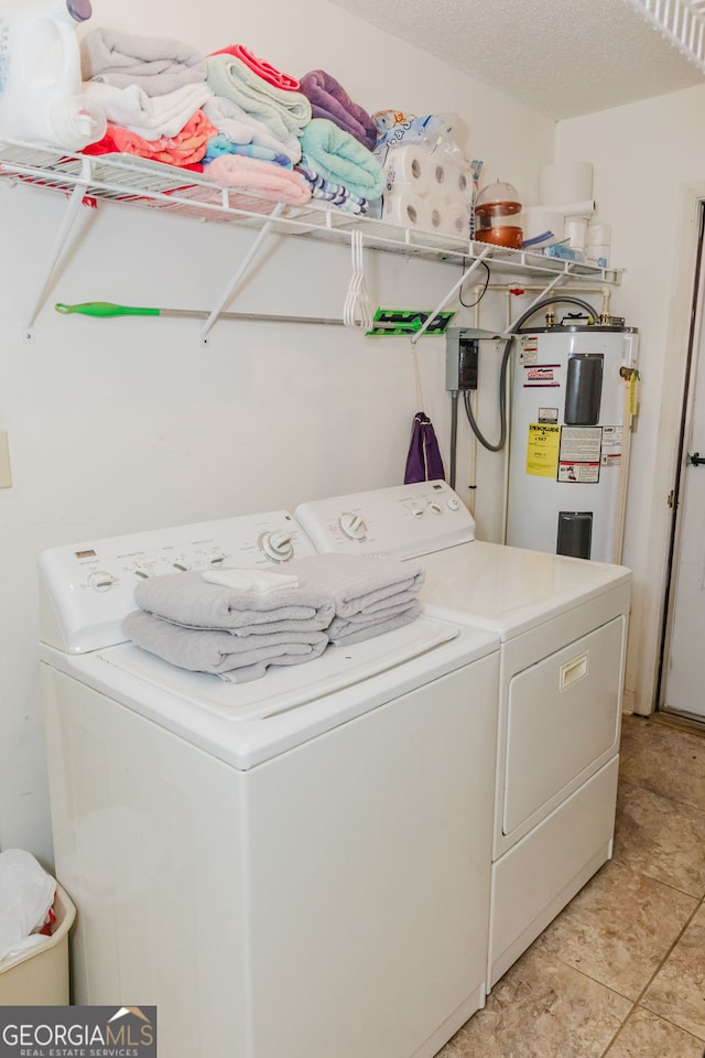 washroom featuring water heater, light tile patterned flooring, a textured ceiling, and independent washer and dryer