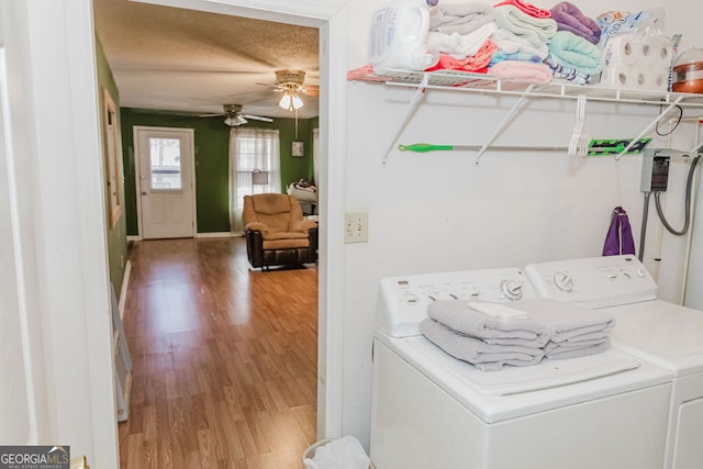 clothes washing area featuring washing machine and clothes dryer, ceiling fan, wood-type flooring, and a textured ceiling