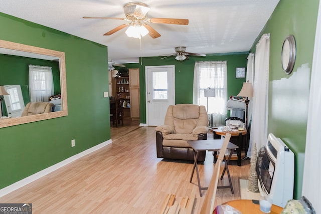 living room featuring heating unit, ceiling fan, and light hardwood / wood-style floors