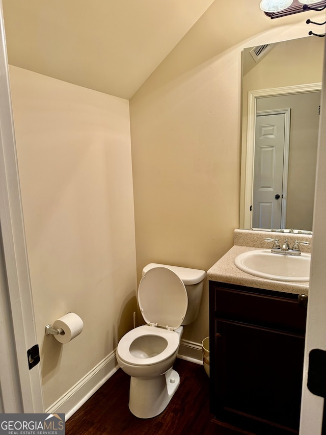 bathroom featuring wood-type flooring, vanity, toilet, and lofted ceiling