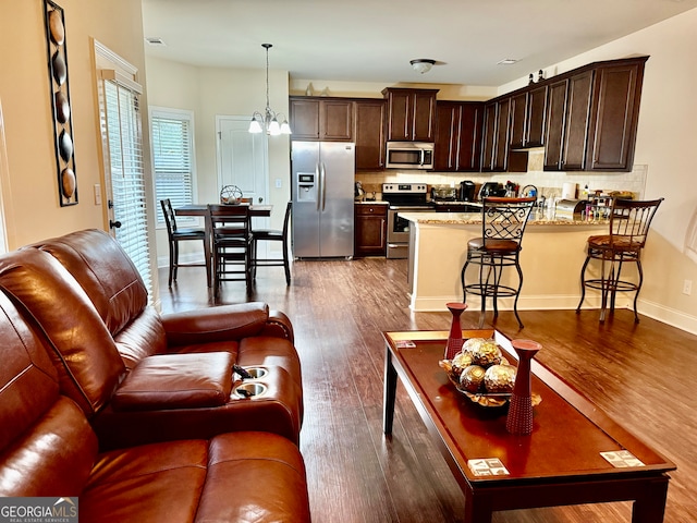 living room with dark hardwood / wood-style flooring and an inviting chandelier