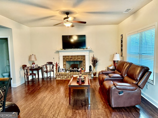 living room featuring ceiling fan, dark hardwood / wood-style floors, and a fireplace