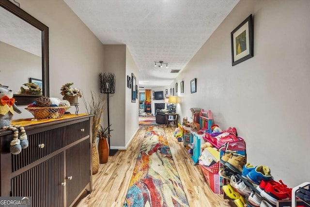 corridor featuring a textured ceiling and light hardwood / wood-style flooring