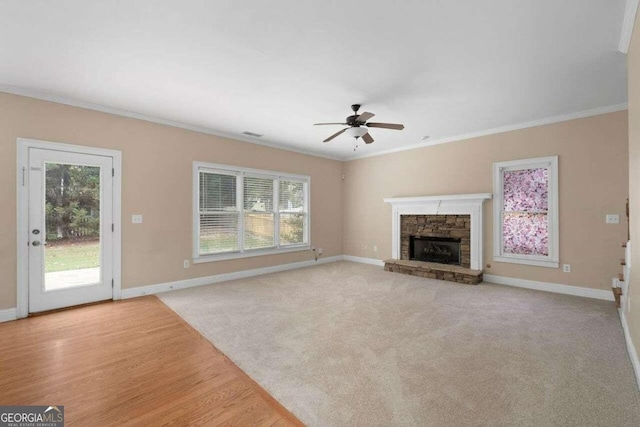 unfurnished living room with a stone fireplace, light hardwood / wood-style floors, ornamental molding, and ceiling fan