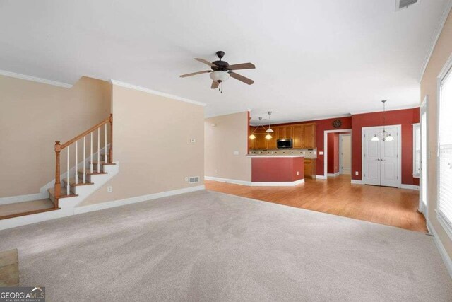 unfurnished living room featuring light hardwood / wood-style floors, ceiling fan with notable chandelier, and ornamental molding